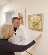 Prof. Dr. Christian Langer, Chefarzt der Klinik für Hämatologie und Onkologie und Ärztlicher Direktor am Klinikum Kempten bedankt sich für die farbenfrohe Ausstellung auf der Onkologischen Station bei Gisela Schultze-Bachmann